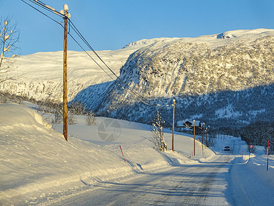 日出时驾车穿过挪威的山脉和森林雪景太阳金光金子街道极夜运输爬坡速度景观图片