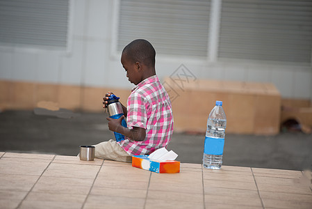 小男孩坐在阳台上 手拿着一瓶水图片