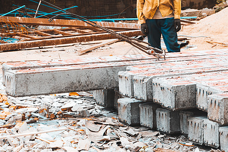 地面工人通过在建筑工地上抛滚而移动的混凝土柱子图片