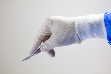 手术刀握在白色背景上 工作室拍摄 手术设备 外科手术程序采摘治疗手术台医生乐器切口手套诊所金属药品图片