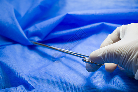 医生手中的手术钳 在蓝色背景下 工作室拍摄 操作设备 手术过程手套程序医院诊所实验室解剖学乐器刀刃外科钳子图片