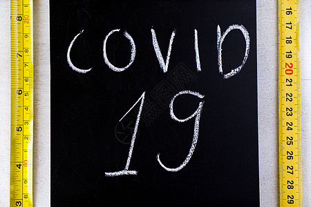 黑板上的黄金属标尺和Covid 19文字图片