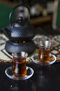 手拿着黑茶和茶壶 土耳其茶杯树叶文化时间草本植物饮料仪式玻璃静物杯子液体背景图片