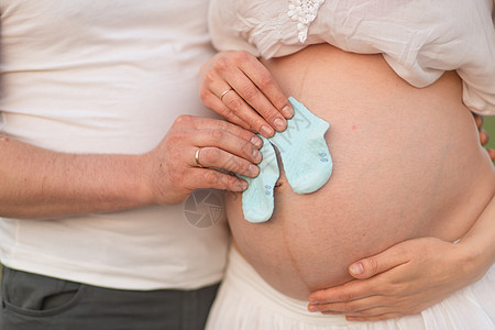 怀孕的快乐时光 怀孕少女怀着新生儿男孩 夫妇们为婴儿买了蓝袜子 笑声母性父母短袜拥抱母亲妻子公园女性家庭男性图片