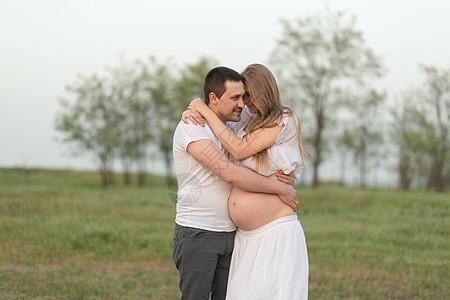 怀孕的快乐时光 一位慈爱的丈夫和他怀孕的妻子在远离城市的新鲜空气中婴儿成人母性拥抱男性女性生活肚子短袜父亲图片