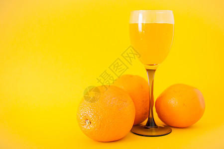 明亮的橙子和一杯橙汁 在明亮的黄色背景上 健康的生活方式概念图片