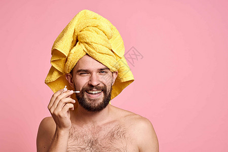 海绵头上有黄毛巾的男人 干净的皮肤护理粉红色背景浴室男生身体成人眼睛卫生头发温泉微笑奶油图片