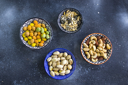 桌子上碗里的蛋白质 杏仁 腰果和蓝底的海绵坚果种子开心果胡桃榛子花生核桃营养食物盘子零食图片
