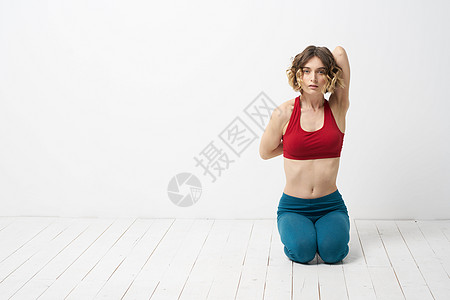 女孩在轻光背景下做瑜伽 用他的双手穿红色T恤领汗衫身体健身房成人女士姿势福利工作室冥想健康专注图片