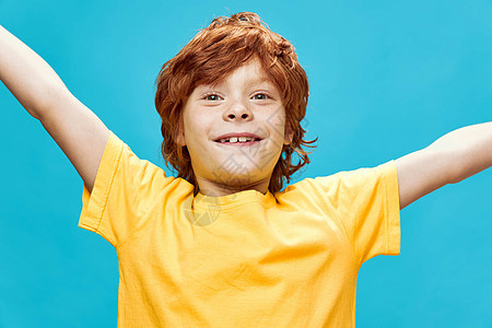 红发男孩满脸欢喜的红头发男孩 散开的双臂黄色T恤紧身乐图片