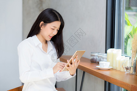 使用平板电脑的年轻年轻女性 在Th闲暇微笑人士桌子阅读货币女士咖啡店女孩咖啡图片