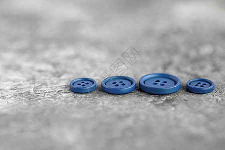 混凝土背景上的蓝色毛垫按钮风格针线活主义者纺织品宏观衣服缝纫团体塑料工艺图片