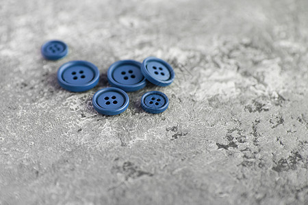 混凝土背景上的蓝色毛垫按钮艺术圆圈衣服装饰主义者团体风格塑料纽扣缝纫图片