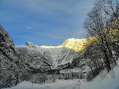 日出时驾车穿过挪威的山脉和森林太阳公路太阳光线阳光景观金光街道速度爬坡晴天图片