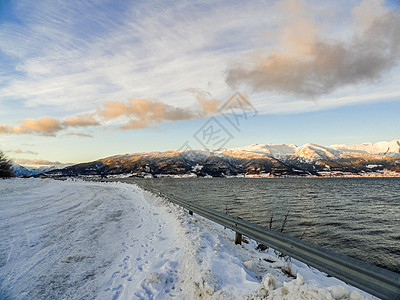日出时驾车穿过挪威的山和海湾图片