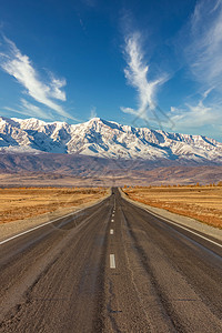通往 Kuray 山脉雪峰的一条笔直的空旷高速公路的肖像尺寸照片 美丽的蓝色多云天空作为背景 阿尔泰山脉 西伯利亚 俄罗斯图片