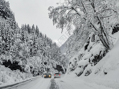 在挪威的雪路和风景中行驶天气乡村交通木头旅行暴风雪森林运输小路国家图片