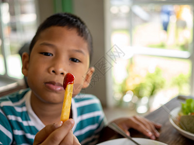 炸薯条加番茄酱 在男孩手里盘子桌子美食男生食物土豆垃圾享受小吃女士图片