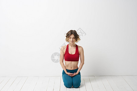 一名穿蓝牛仔裤的女子在室内浅背景和体操中做瑜伽 而且体操机身微弱成人工作室福利力量健康专注姿势沉思平衡运动图片