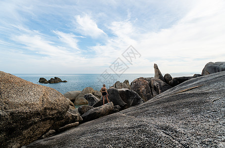 星空大海穿着白色T恤长发的年轻人 站在岩石上享受海洋景色 旅行 在旅途中海景晴天游客日出自由冒险旅游蓝色幸福日落背景