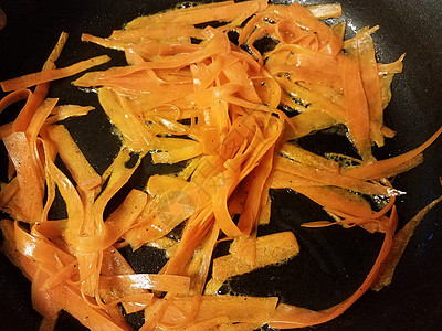 煎锅油中的橙色胡萝卜条背景图片