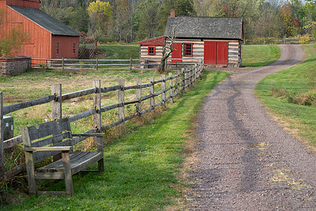 碎石路经过一个空的长凳 红色谷仓和木屋图片
