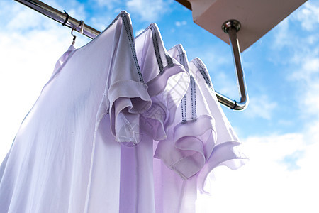 白T恤在衣绳上 对着蓝天衣服洗衣店衬衫夹子天空微风蓝色工作生态衣夹图片