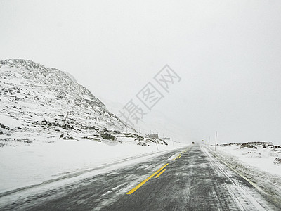 穿过暴风雪的暴风雪 用黑冰在路上 挪威季节运输小路冻结风暴交通乡村黑冰风景森林图片