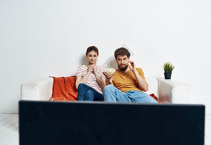 一男一女坐在电视前沙发上 一朵绿花在室内的锅里妻子女性丈夫电影家庭女士房间长椅技术男人图片