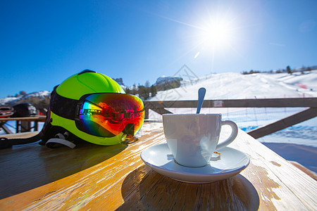 卡布奇诺咖啡在滑雪度假胜地咖啡馆咖啡厅桌子高山杯子咖啡店蓝色太阳咖啡旅行风镜天空图片