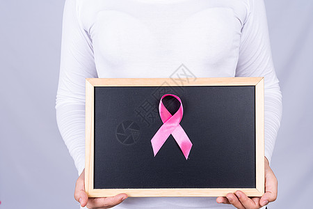 由妇女持有的黑板上的乳腺癌认识丝带 医疗 广告概念保健等信息学知识帮助女性女孩机构化疗生活生存预防组织治愈图片