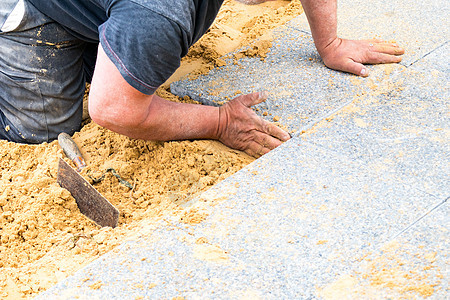 泥瓦匠在沙滩上打碎砂砾石板 以建立小巷地面园林工人工具绿化建筑学安装石工石匠建筑图片