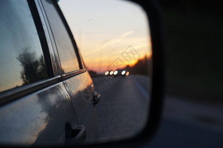 汽车后视镜中的模糊道路和日落图片