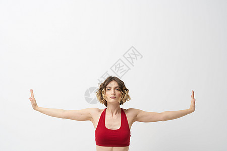 女孩在轻光背景下做瑜伽 用他的双手穿红色T恤领汗衫工作室沉思闲暇成人身体运动力量女士专注训练图片