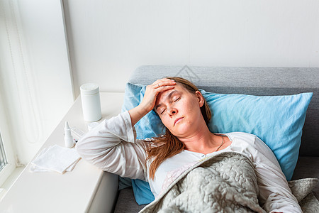 躺在毯子下的头痛和发烧的病妇 在冠状病毒大流行期间 生病的妇女卧床不起症状条件医院卧室卫生压力伤害保健女性成人图片