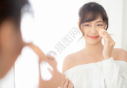 肖像美丽的年轻亚洲女人 用粉末泡芙在che卧室镜子腮红美容皮肤护理容貌治疗女士敷料图片