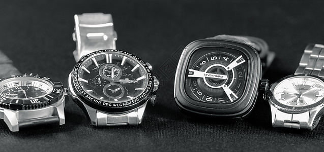 四只手表在深灰色表面排成一列图片