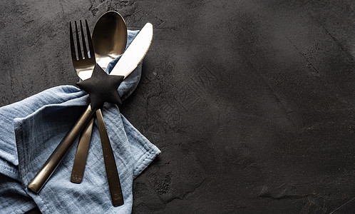 黑色背景的餐盘设置勺子餐巾盘子金属食物星形石头银器桌子图片