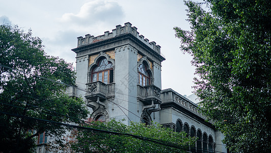 在墨西哥城一些树丛后面的中世纪观望建筑树叶阳台拱门中心树木蓝色建筑物天空阳光叶子图片