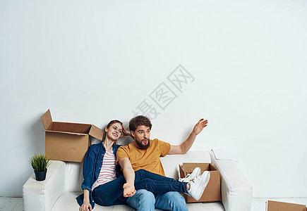 白沙发上有一对年轻夫妇 和一盒有趣的聊天家庭男人妻子控制女朋友娱乐幸福女性成人拥抱图片