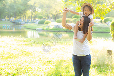 美丽的年轻年幼母亲带着微笑的小女儿 带着小女儿享受乐趣草地拥抱女士女孩母亲家庭脖子女性图片
