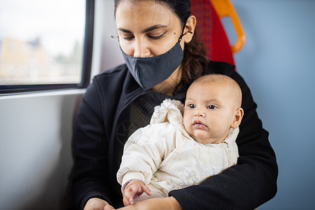 妇女坐在一辆公共汽车窗户旁边 将婴儿抱在她的怀里应急快乐父母家庭妈妈童年孩子旅行母亲车辆图片