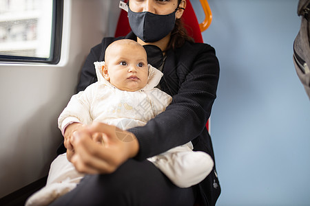 婴儿躺在母亲的腿上 她的母亲坐在公共汽车窗户旁边女士运输成人民众女性快乐童年妈妈旅行车辆图片