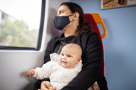 女人透过公共汽车的窗户看着她 抱着她微笑的婴儿母性女士女性车辆旅行父母妈妈应急运输民众图片