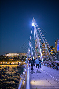 夜里从有行人行行走的桥梁扶手处城风建筑学电缆口罩景观旅行反射天空城市灯光行人图片