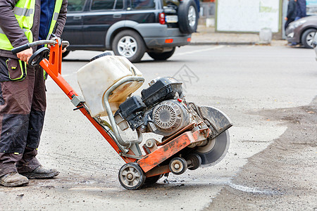 一名工人将装有金刚石切割轮的汽油切割机移到需要维修的坏路段图片