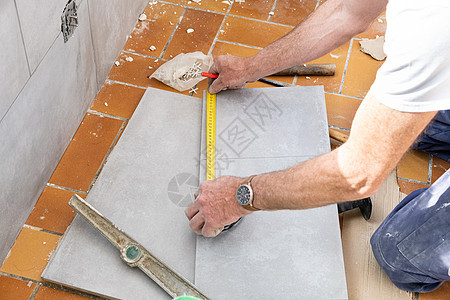 瓷砖在剪裁前先测量瓷砖刀具男人地板地面安装工人材料制品铅笔工作图片