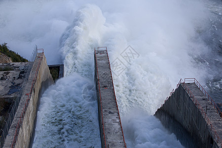 俄罗斯马加丹地区的科雷马水电站 从水力发电站的大坝溢洪道 一条巨大的水流在高山的背景下流入河流车站水库蓝石发电机工程活力阳光天空图片