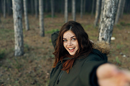 身穿温暖衣衣的美丽女人 在秋天森林背景上伸展了手 穿着温暖外套图片