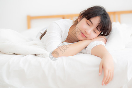 美丽的亚洲年轻女子疲倦睡在床上舒舒服服成人闲暇女孩房子时间快乐活动女性唤醒休息图片